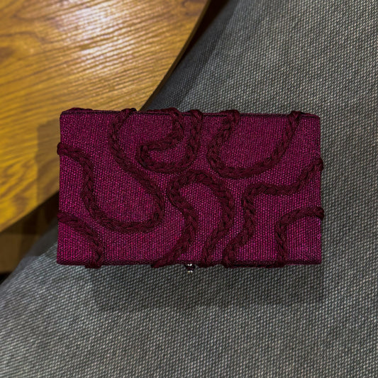 burgundy asooke clutch abstract braided design on a gray surface